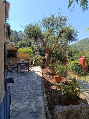 une terrasse avec une table, des plantes et un arbre dans l'établissement un coin paisible, à Saint-Cézaire-sur-Siagne