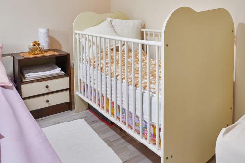 a white crib in a bedroom with a nightstand at Vila Magnolia in Bijela
