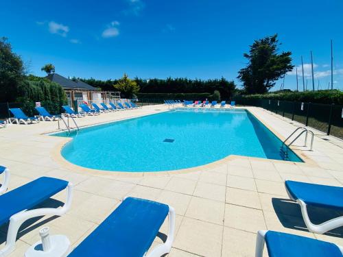 une grande piscine avec des chaises longues bleues dans l'établissement Charmant T2 5 personnes, à Arzon
