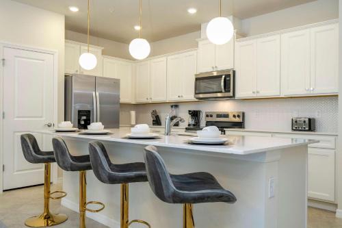 a kitchen with white cabinets and a large island with bar stools at Modern and Spacious 5BR Villa Near Disney with Private Pool and Themed Bedrooms in Orlando
