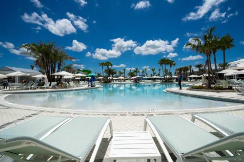 a large swimming pool with chairs and palm trees at Modern and Spacious 5BR Villa Near Disney with Private Pool and Themed Bedrooms in Orlando