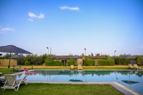 a pool with chairs and umbrellas in a yard at Oléa villa & lodge in Marrakesh