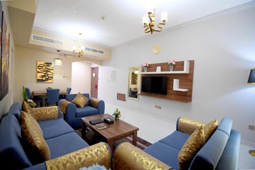 a living room with blue couches and a tv at Emirates Stars Hotel Apartments Dubai in Dubai