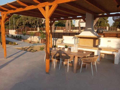 a wooden gazebo with a wooden table and chairs at Alestone Villa by the sea in Vasilikos