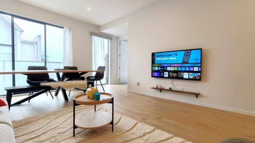 a living room with a table and a tv on a wall at Brand New Spacious 5BR Home in Central AKL in Auckland