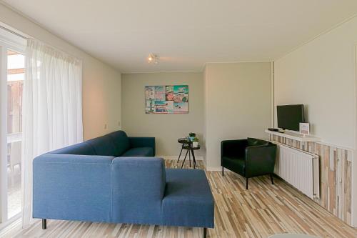 a living room with a blue couch and a television at Hoeve Noord & Zuid - Familie Arrangement in Ons Belang