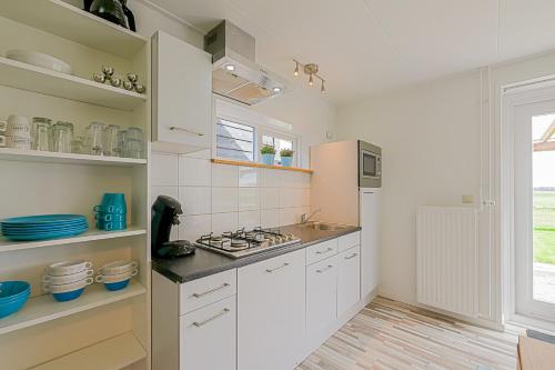 a kitchen with white cabinets and a stove top oven at Hoeve Noord & Zuid - Familie Arrangement in Ons Belang