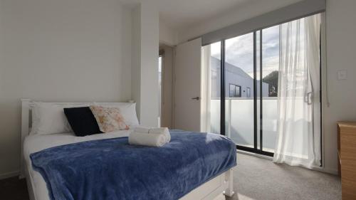 a bedroom with a bed and a large window at Brand New Spacious 5BR Home in Central AKL in Auckland
