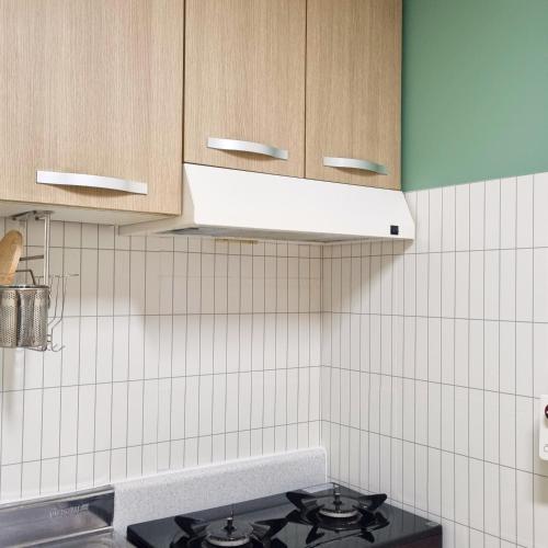 a kitchen with a stove and a white tiled wall at Forest Sillim - private room in Seoul