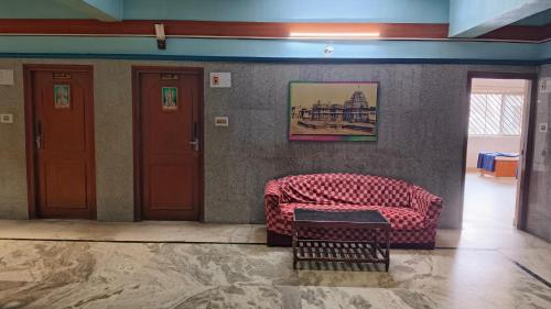 a red couch in a room with a wall at vishnuregencybelur in Belūr