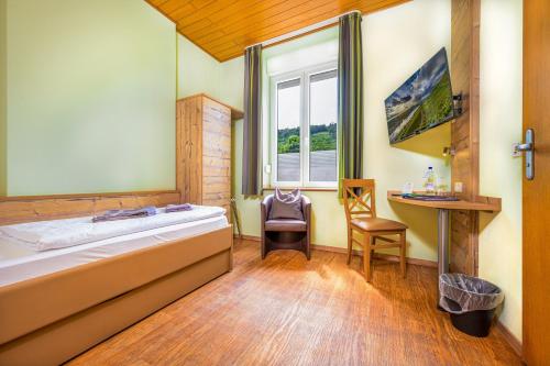 a room with a bed and a desk and a window at Altes Schulhaus in Zeltingen-Rachtig