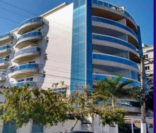 un grand bâtiment avec des arbres devant lui dans l'établissement Cabo Frio Espaço Girassol, à Cabo Frio