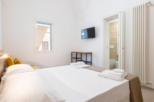a white bedroom with a bed with towels on it at Casa Agata in Leverano