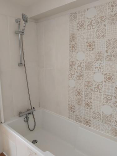 a white bath tub with a shower in a bathroom at Spacious 3 bedroom house 250m from Saint-Suliac's beach in Saint-Suliac