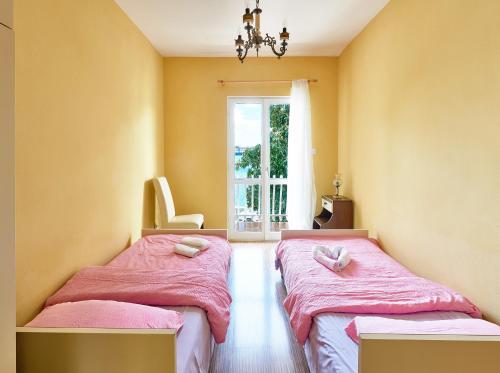 a bedroom with two beds with pink sheets and a window at Vila Magnolia in Bijela