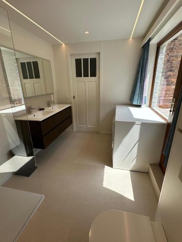 a bathroom with a sink and a toilet and a mirror at In De Wulf in Ypres