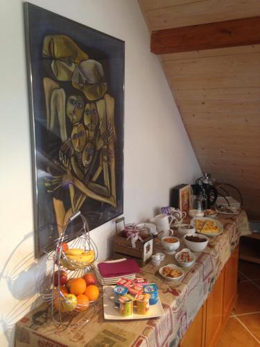 een tafel met eten en een schilderij aan de muur bij B&B Le Sourire du Lac in Sévrier