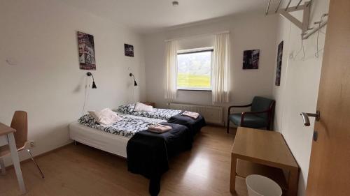 a bedroom with a bed and a desk and a window at Kirkjufell Guesthouse and Apartments in Grundarfjordur
