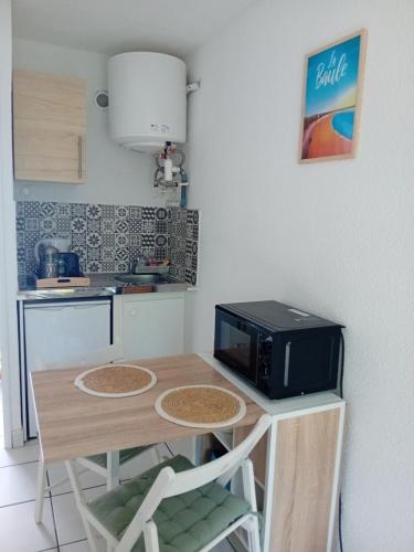 une petite cuisine avec une table et un four micro-ondes. dans l'établissement Appartement cosy proche plage, à Saint-Nazaire