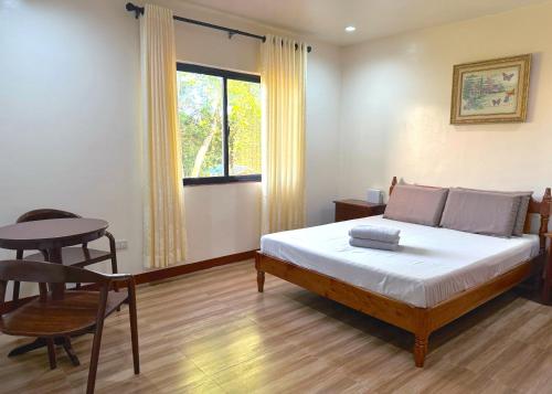 a bedroom with a bed and a table and a window at Tessie's Home Stay Bed & Breakfast in Puerto Princesa City