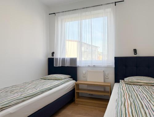 two beds in a small room with a window at Chatka Morska 3 Apartamenty in Karwia
