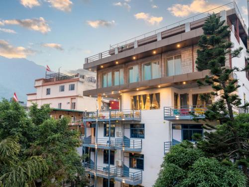 ein hohes weißes Gebäude mit Balkonen und Bäumen in der Unterkunft Moustache Hostel Rishikesh in Rishikesh