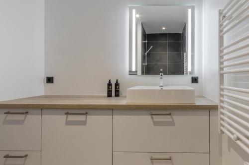un bagno bianco con lavandino e specchio di Studio Kayla - Espace bien-etre Piscine Face au Kandahar a Les Houches