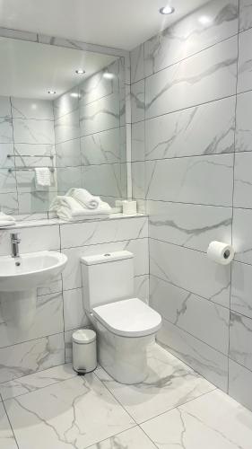 a white bathroom with a toilet and a sink at Killarney Court Hotel in Killarney