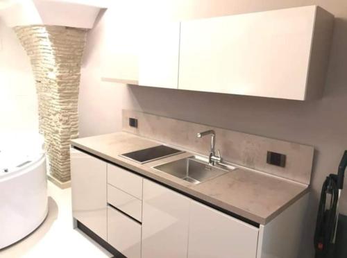 een keuken met witte kasten en een spoelbak bij Via Montecastello Emotional Room in Termoli