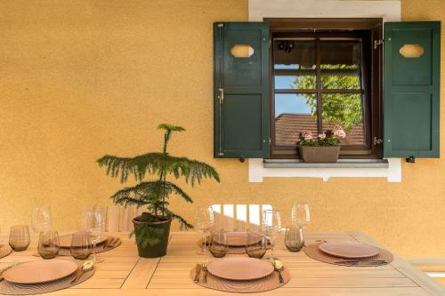 a table with plates and glasses and a plant on it at Garden House 202 by Sigismundi in Brežice