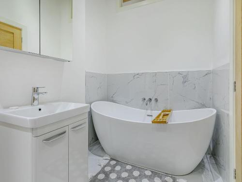 a white bathroom with a tub and a sink at Howell Hall Barn in Howell