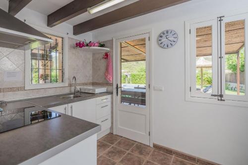 een keuken met witte kasten en een klok aan de muur bij La Rafal in Pollença