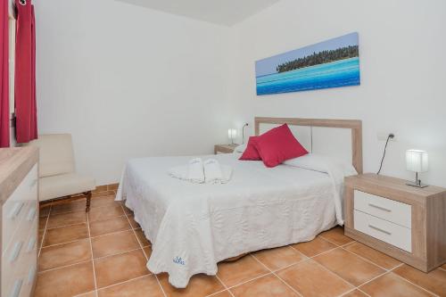 een slaapkamer met een wit bed met rode kussens bij La Rafal in Pollença