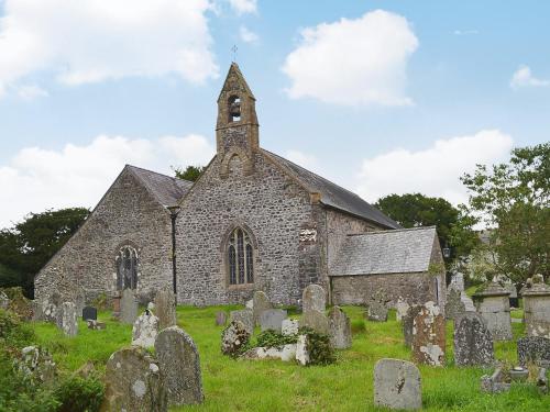 an old stone church with a clock tower in a graveyard at The Old Post Office in Myddfai