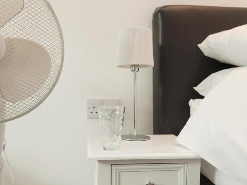 a nightstand with a glass vase on it next to a bed at Swallows Nest in Wool