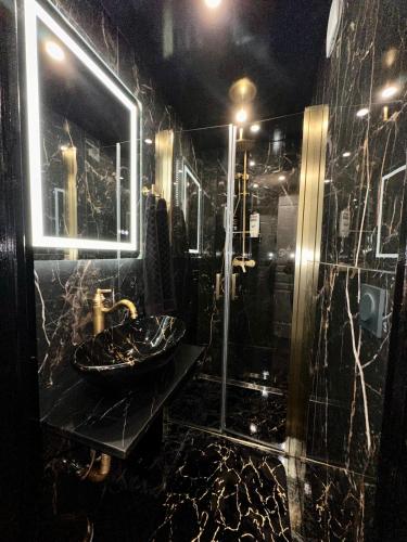 La salle de bains noire est pourvue d'un lavabo et d'une douche. dans l'établissement SWEET DREAMS Love room & Spa, à Villeneuve-le-Roi