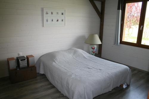 Un dormitorio con una cama y una lámpara y una ventana. en Gite Vercors-Chambaran, en Saint-Marcellin