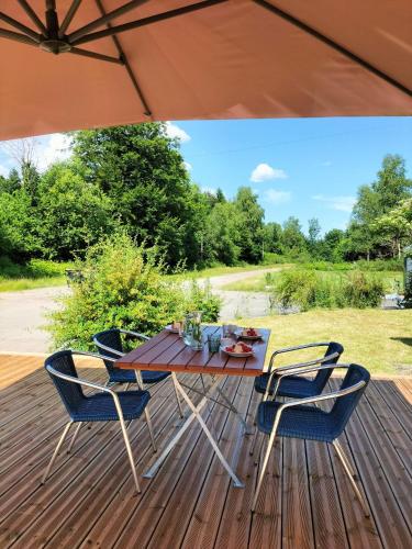 a table and chairs on a deck with an umbrella at B&B Gite les Baudy in Le Haut-du-Them