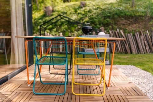 three colorful chairs sitting around a table on a deck at Najwyzej - domek z sauną w Gródku nad Dunajcem nad Jeziorem Rożnowskim in Gródek Nad Dunajcem