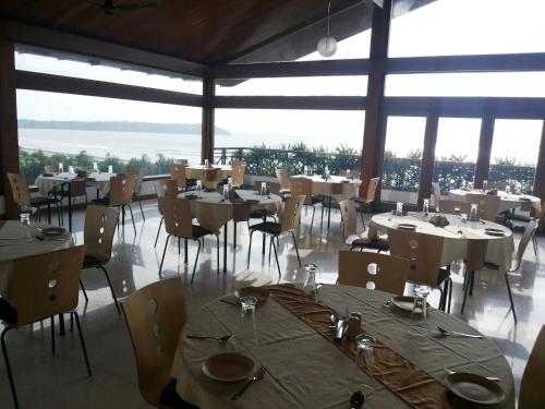 a restaurant with tables and chairs in a room with windows at Varanda Do Mar in Panaji