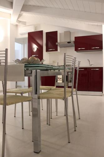 une table et des chaises dans une cuisine avec des armoires rouges dans l'établissement Apartments Arcobaleno, à Deiva Marina