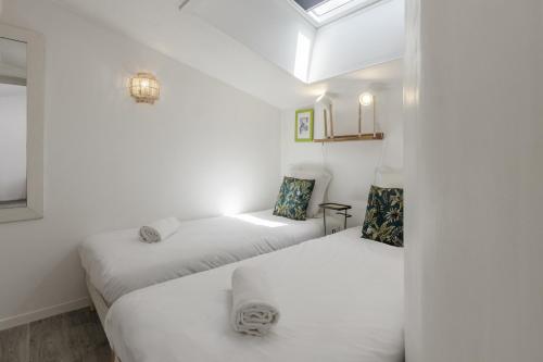 deux lits dans une chambre aux murs blancs dans l'établissement Le Triolet - Centre-ville - Balcon avec vue, à Chamonix-Mont-Blanc