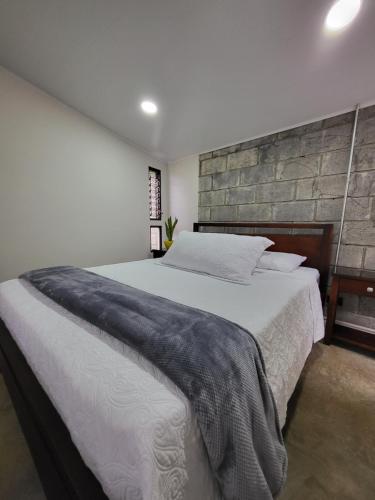 a bedroom with a large bed with a stone wall at Casa del Cafe-Familiar in Heredia