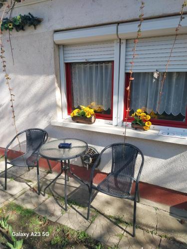 three chairs and a table in front of a window at Repi-Tár apartman in Szolnok