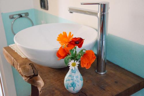 d'un lavabo et d'un vase avec des fleurs sur une table. dans l'établissement Alba dei Due Soli B&B, à Nocera Umbra