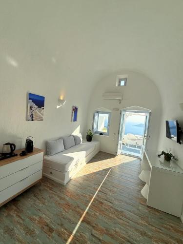 a white living room with a white couch and a window at Sunset Caldera Seaview Houses in Imerovigli