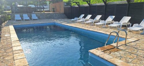 a swimming pool with chairs and a pool of water at Ra-C&C in Vrdnik