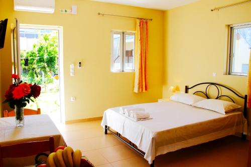 a bedroom with a bed and a vase of flowers at Dimitra Rooms in Lefkada Town