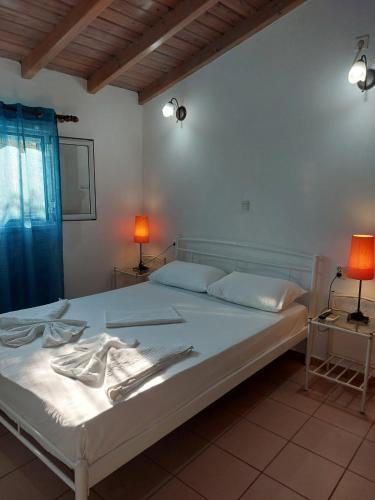 a bedroom with a bed with white sheets and two lamps at Soldatos Rooms in Marantochori