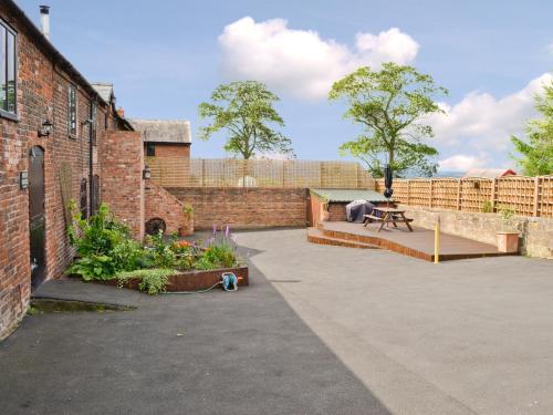 a courtyard with a brick building with a bench and flowers at The Old Stables in Helsby